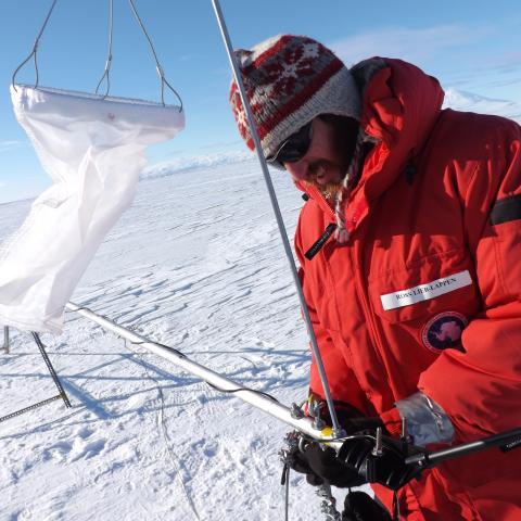 A man sets up scientific equipment in the Antarctic