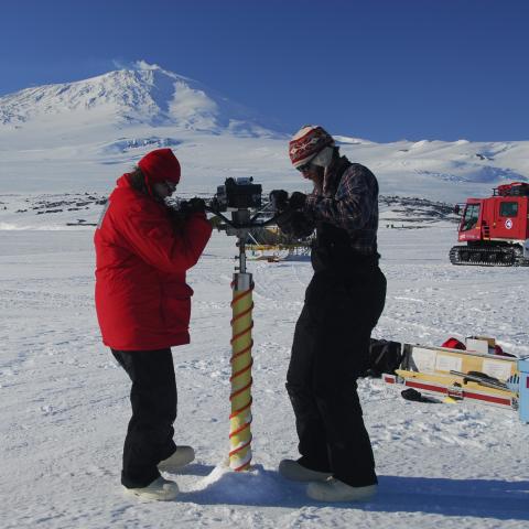 Two men drill for ice core samples in the Antarctic
