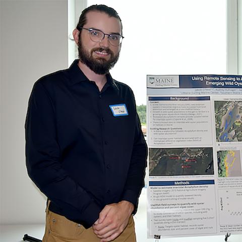 A college student standing in front of a scientific poster