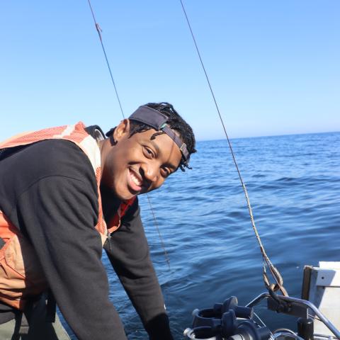 A smiling college student on a boat.