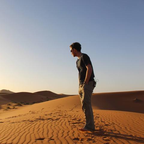 A young man stands in the desert