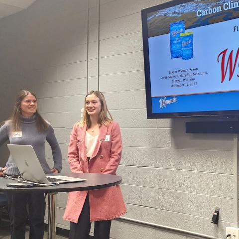 Three students present in front of a screen