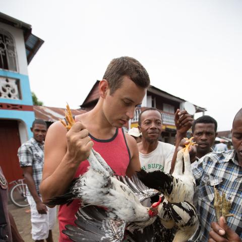 A young man in a village in Madagascar holds a chicken