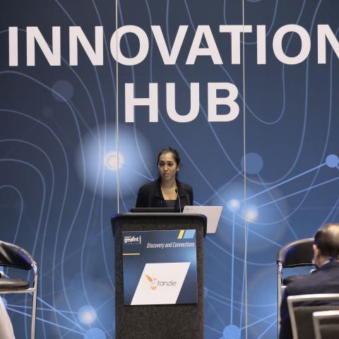 A woman stands at a lectern at an innovation conference