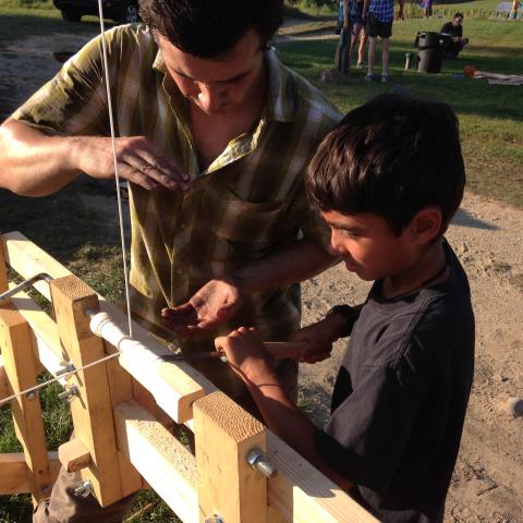 A man and a boy at a wood lathe.