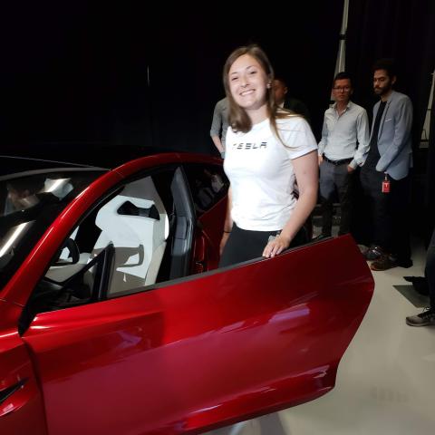 A woman stands alongside a Tesla Roadster