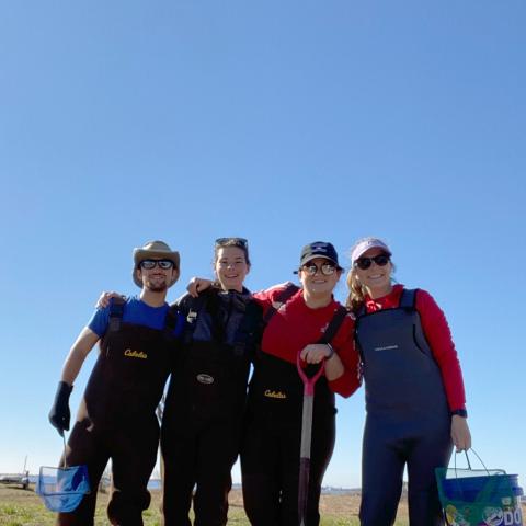 Four college students in a field holding scientific collection equipment