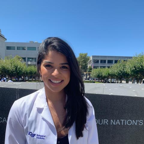 A University of California San Francisco Medical School student in a white jacket standing outside