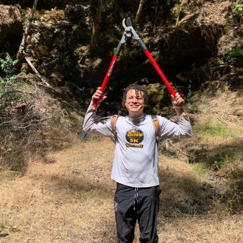 A person holds a pair of lopping shears above their head.