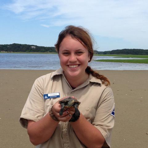 A young woman holds a baby sea turtle