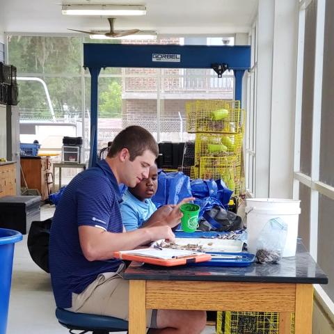 A college student and a young boy in an environmental lab.