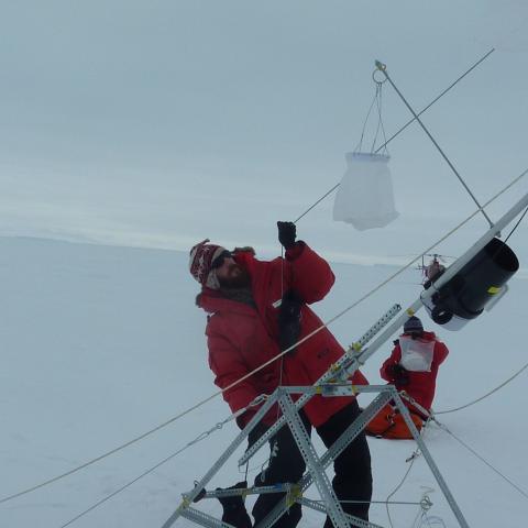 A man sets up scientific equipment in the Antarctic