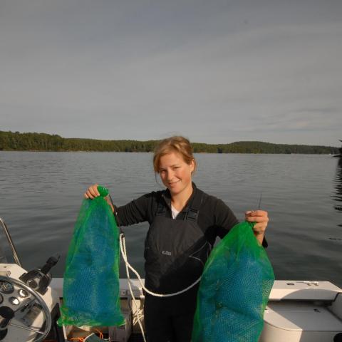 A woman on a ship holds a pair of spat bags