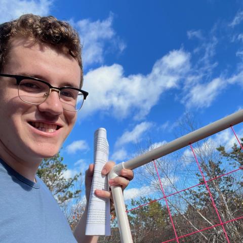 A young man holds a paper and research equipment