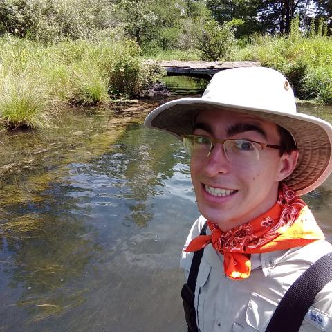 A man stands near a river