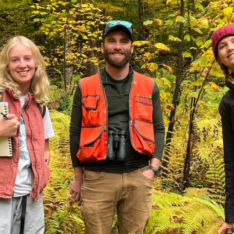 Three people standing in a forest.