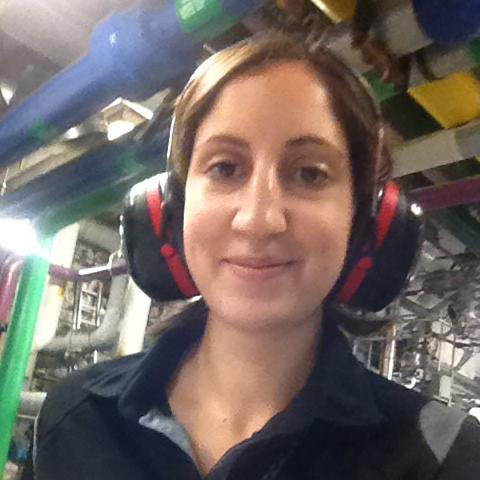 A woman in a mechanical room holding a notepad