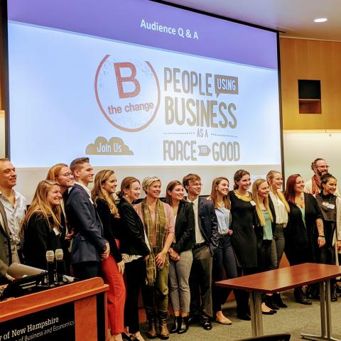 A group of students in front of a projector screen in a lecture hall.