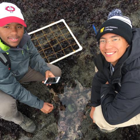 Students smile while huddled over a tidal pool.