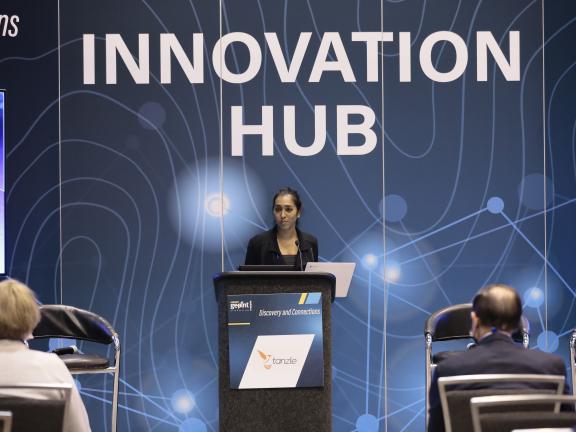 A woman stands at a lectern at an innovation conference
