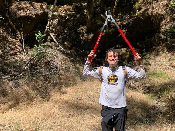 A person holds a pair of lopping shears above their head.