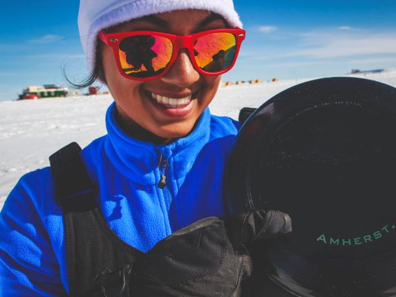 A woman stands in a field of Arctic snow and holds a camera