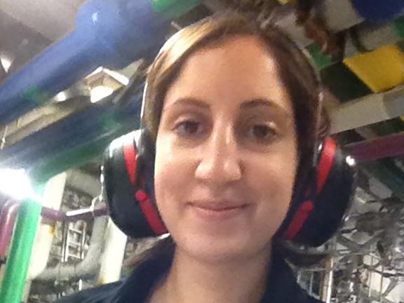 A woman in a mechanical room holding a notepad